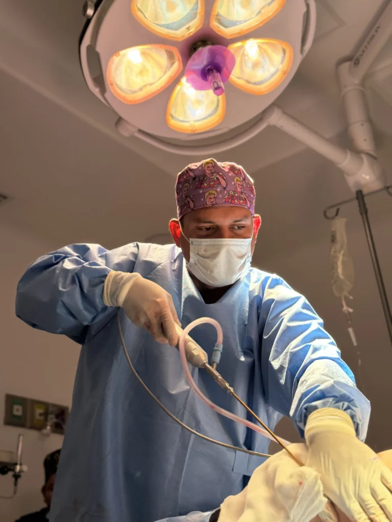 Board-certified plastic surgeon performing liposuction surgery in a sterile Tijuana operating room.